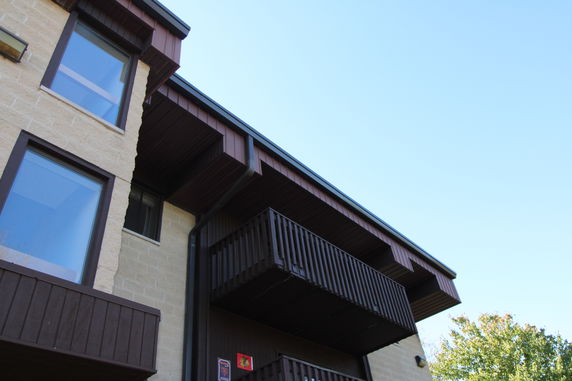 View of a building facade with brown wooden balconies and large windows.