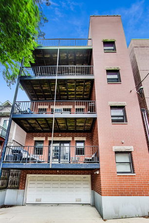 Front view of a multi-story brick building with balconies and a garage.