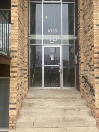 Entryway of a brick building with glass doors and visible stairs