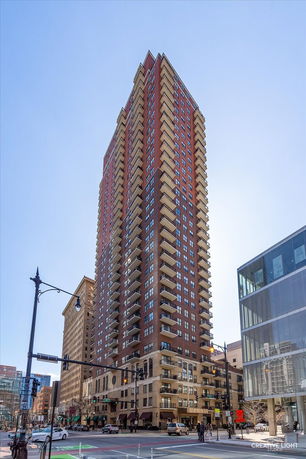Front view of a tall residential building with multiple balconies in an urban setting.