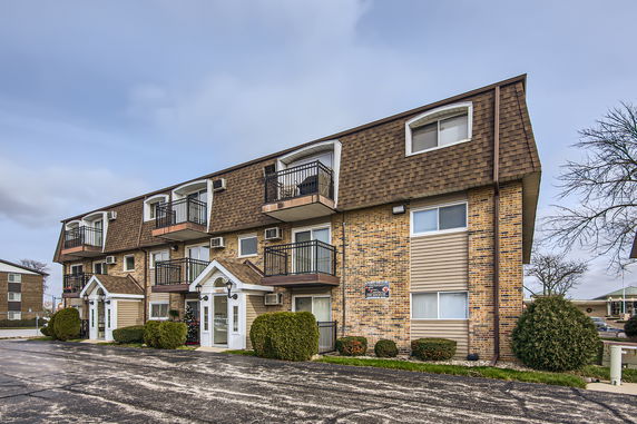 Front view of a multi-story brick apartment building with balconies.