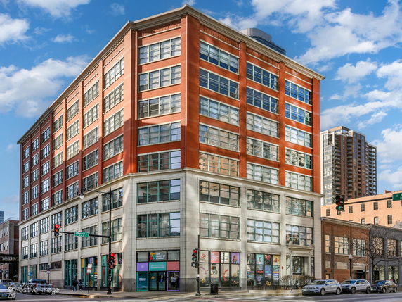 Front view of a multi-story brick building with large windows.