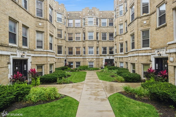 Front view of a multi-story brick building with multiple windows and a courtyard.