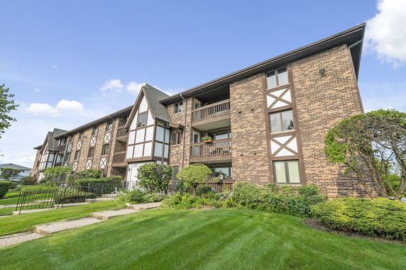 Front view of a multi-story residential building with brick and wooden accents.
