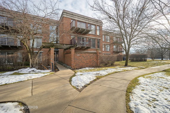 Front view of a multi-story brick apartment building with balconies.