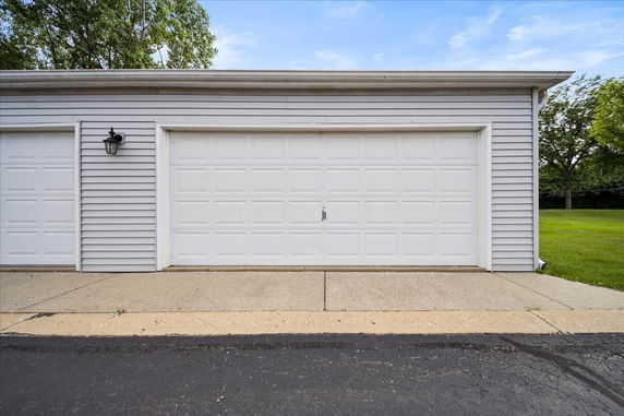Front view of a garage with white double door and siding.