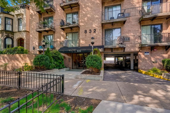 Front view of a multi-story brick apartment building with balconies and a central entrance.