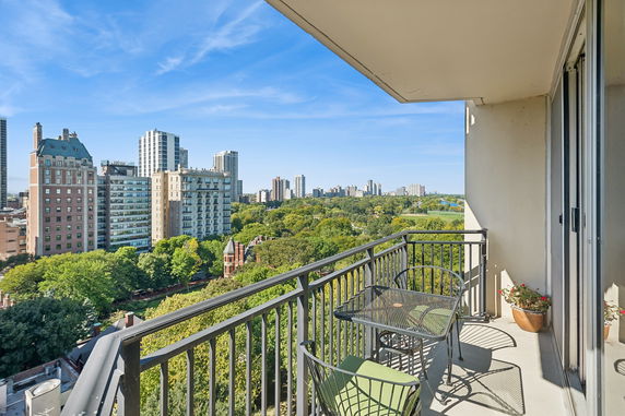 View from a balcony overlooking a cityscape with high-rise buildings and a park.