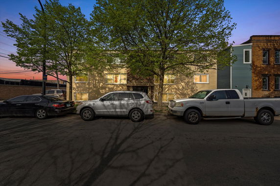 Front view of a multi-story apartment building with parked cars in front.