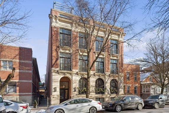 Front view of a three-story brick building with large windows and a decorative facade.