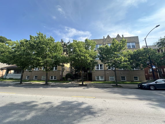 Front view of a multi-story brick building with trees in front.