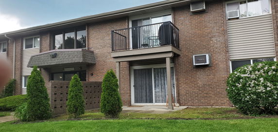 Front view of a two-story brick building with balconies and sliding doors.