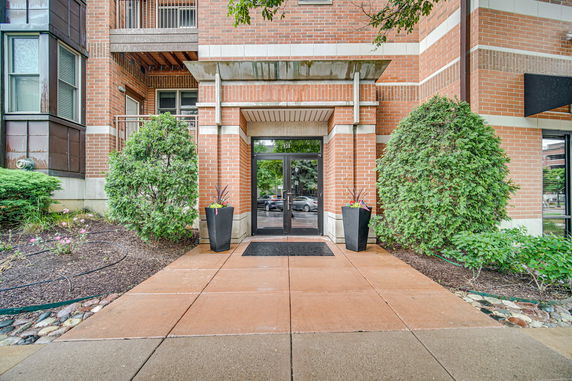 Front view of a building entrance with brick facade and glass doors.