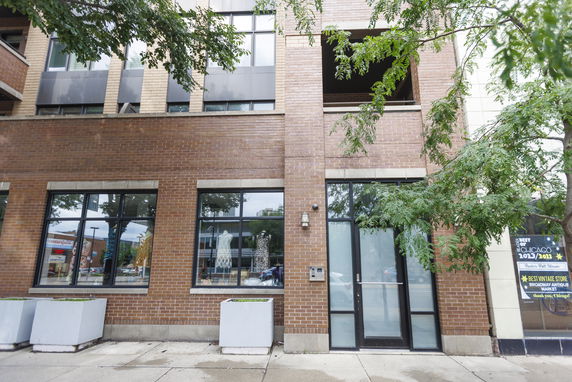 Front view of a brick building with multiple windows and a glass door.