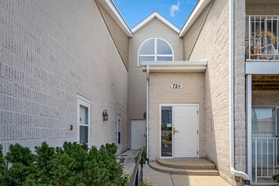 Front view of a building entrance with a white door and arched window above.