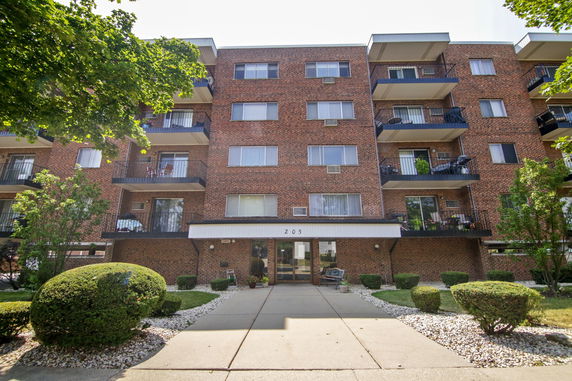 Front view of a multi-story brick apartment building with balconies.