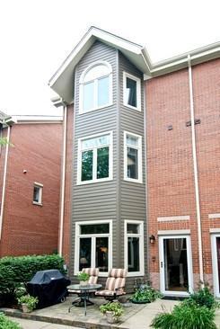 Back view of a three-story house with large windows and patio area.