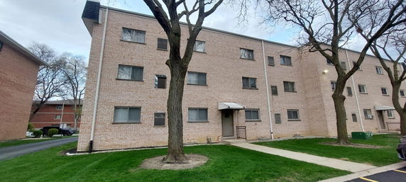 Front view of a multi-story apartment building with a brick exterior.