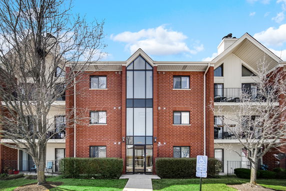 Front view of a three-story brick apartment building with large windows.
