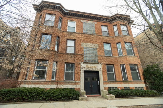 Front view of a multi-story brick building with several windows and a main entrance.