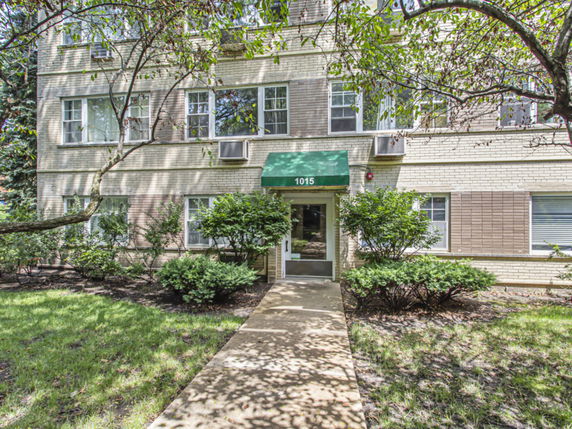 Front view of a multi-story brick building with a green awning over the entrance.