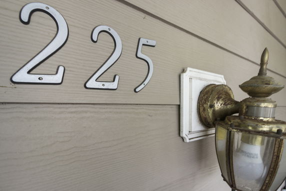 Close-up of a house number 225 with an outdoor light fixture.