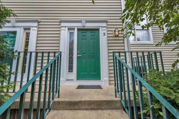 Front view of a house with a green door and beige siding.