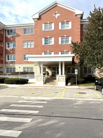 Front view of a multi-story red brick building with white trim and a covered entrance.