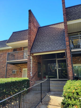 Front view of a brick apartment building with balconies and a covered entrance.