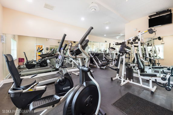 Interior view of a gym with various exercise equipment and mirrors on the walls.