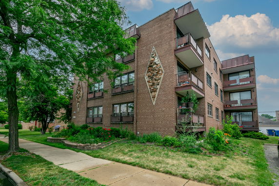 Front view of a multi-story brick apartment building with balconies.