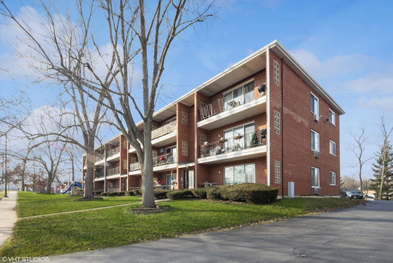 Front view of a three-story red brick apartment building with balconies.