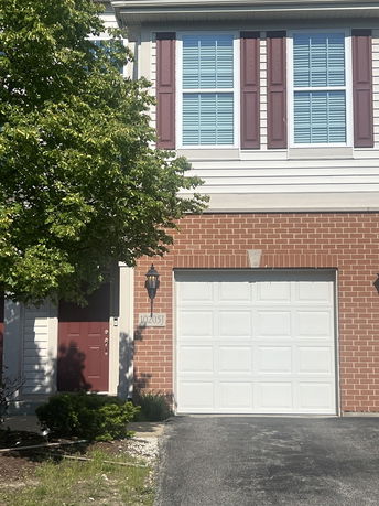 Front view of a house with red brick facade and a single garage door.