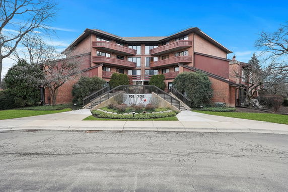 Front view of a multi-story residential building with central entrance and balconies.