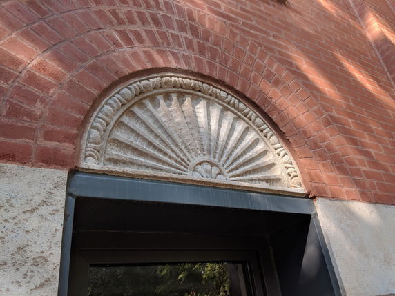 Detail of an arched brick window with decorative stonework.