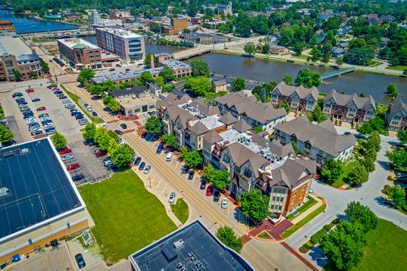 Aerial view of a residential area near a river with multiple buildings and parking lots.