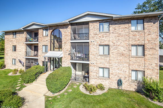 Front view of a multi-story brick apartment building with balconies.