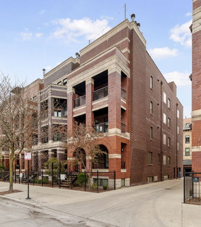 Front view of a multi-story brick apartment building with balconies.