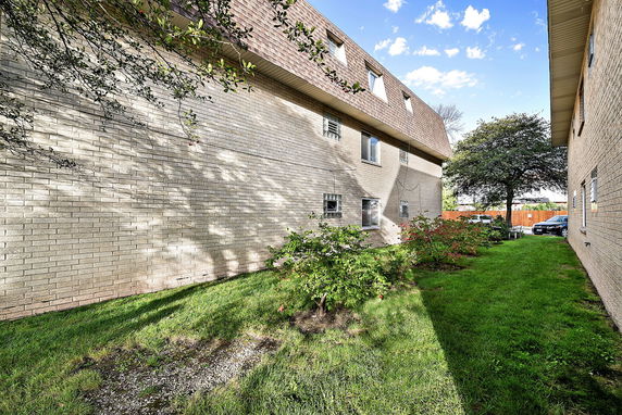 Side view of a two-story brick building with dormer windows.