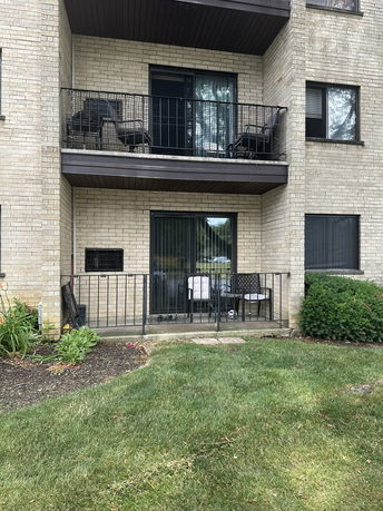 Front view of a brick building with balcony and patio area.