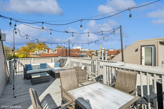 Rooftop deck with seating, tables, and string lights.