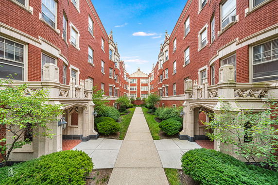 Front view of a red brick apartment building with decorative stone archways.