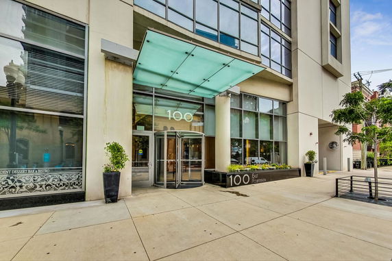 Front view of a modern building entrance with a glass canopy and revolving door.