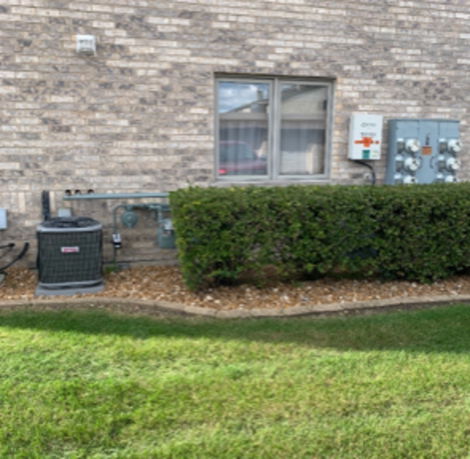 Side view of a brick house with windows and utility meters.