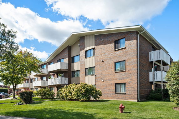 Front view of a multi-story brick apartment building with balconies.