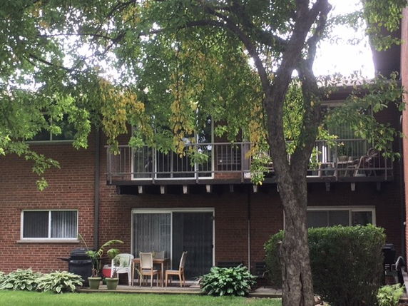 Front view of a two-story brick building with balconies and sliding glass doors.