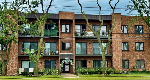 Front view of a multi-story brick apartment building with balconies.