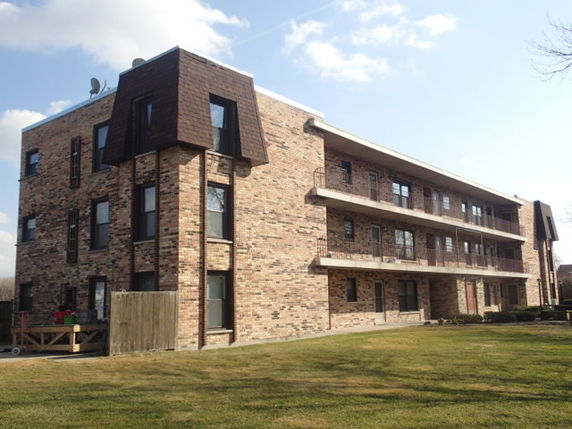Front view of a three-story brick building with balconies.