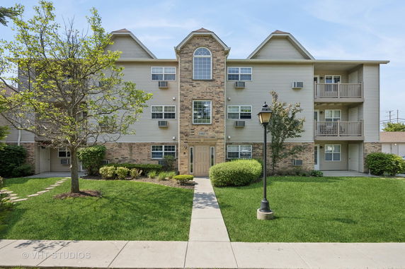 Front view of a three-story apartment building with brick and siding exterior.