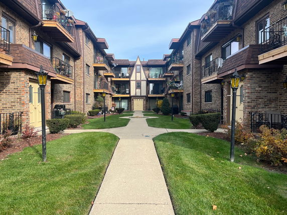 Front view of a multi-story apartment building with balconies and brick facade.